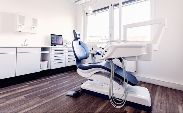 Moderne Zahnarztpraxis mit Behandlungsstuhl, Computer und heller, freundlicher Einrichtung.
